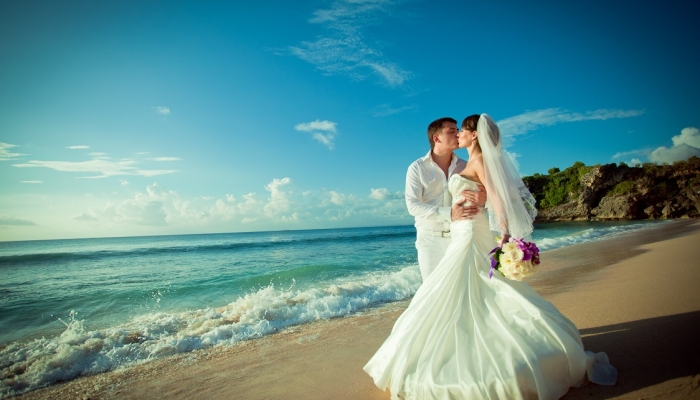 Свадебное фото - на пляже, молодожены целуются